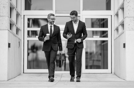 Insurance agent. Two business team men. Man in suit walking across on american office outdoor