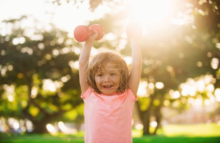 Photo for Happy child exercising outdoor. Boy workout with dumbbell in park. Sporty activity. Kid sport. Active lifestyle - Royalty Free Image