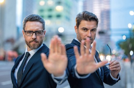 Foto de Crisis, risk. Two handsome business men in suit doing stop sing with hand. Warning expression with negative and serious gesture on the face. Stop hand gesture, businessman says hold on. Bad business - Imagen libre de derechos