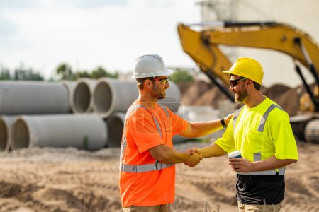 Photo for Two construction site workers in helmet work outdoors. Builders workers working on construction site. The job of a construction site worker requires a lot of physical strength - Royalty Free Image