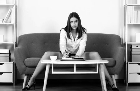 Sexy business woman. Seductive sexy secretary in office. Pretty accountant sensual businesswoman at desk in office interior. Sexy long legs of young accountant woman