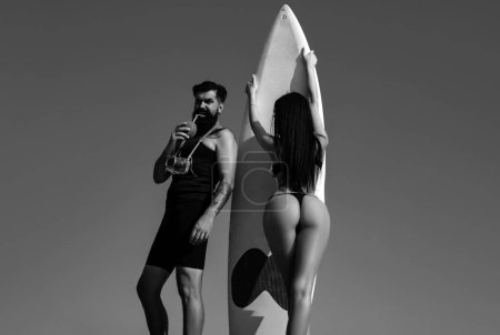 Summer couple vacation. Sexy woman in bikini hold serf board. Summertime concept. Sexy man in swimsuit. Surfboard