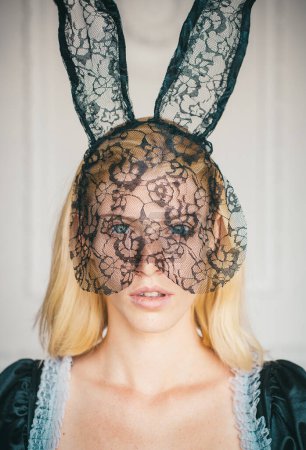 Téléchargez les photos : Jolie jeune femme portant des oreilles de lapin. Portrait de mode de belle femme sensuelle sur fond blanc. Un visage expressif. Pâques de lapin - en image libre de droit