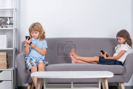 Two children alone with phone at home. Gadget addiction. Mobile addict concept. Parental control, social media addiction. Kids playing on smartphone