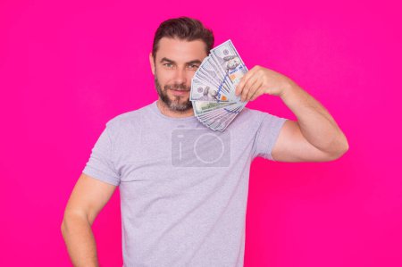 Business man in t-shirt with cash money dollars banknotes isolated on pink studio background. Hundred dollar bill, financial concept