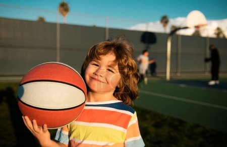 Kid boy concentrated on playing basketball cheerful and pleasant
