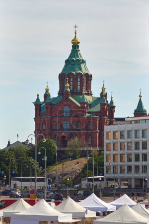 Foto de Finlandia, Helsinki - 16 de julio de 2023. La antigua catedral ortodoxa de Uspenskiy hecha de ladrillo rojo rodeada de modernos edificios urbanos en la ciudad europea de Helsinki. - Imagen libre de derechos