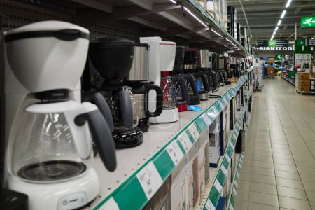 Cafetières et autres machines de cuisine sur les étagères d'un supermarché européen : grande variété, design moderne et fonctionnalité.
