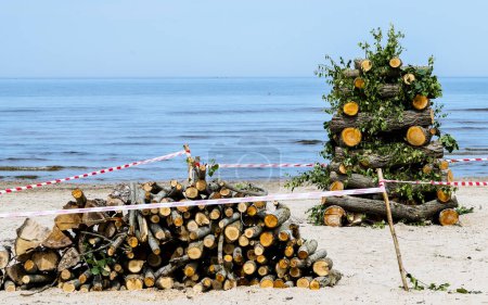 Foto de Playa de arena del Mar Báltico. Cubierta de madera y leña preparadas para un gran fuego para la noche que se utilizará como símbolo de la fiesta tradicional letona del verano - Imagen libre de derechos