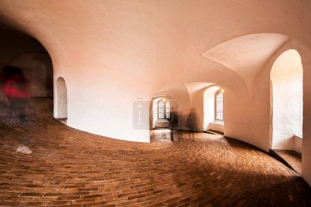 Silhouettes of people in spiral wide corridor in Round Tower or Rundetaarn in Copenhagen, Denmark.