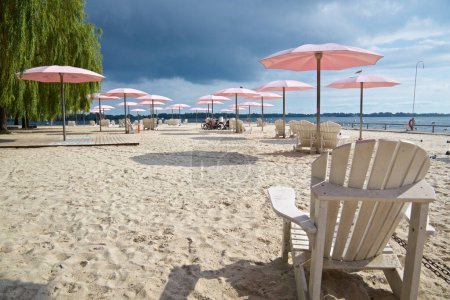 Téléchargez les photos : Ciel nuageux sur la plage avec les parasols roses et les chaises Adirondack - en image libre de droit