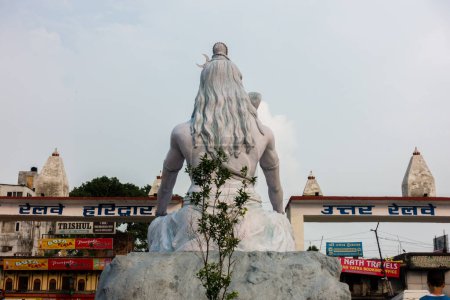 Téléchargez les photos : 4 juillet 2022 Haridwar Inde. Statue du Seigneur Shiva à la gare de Haridwar avec des gens assis tout autour dans l'attente. - en image libre de droit