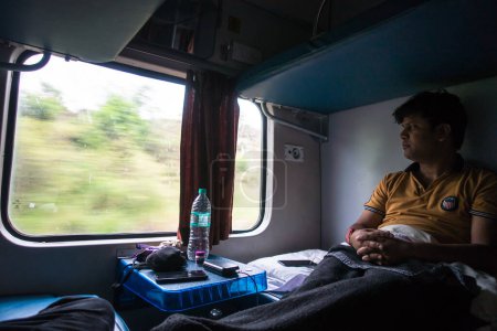 Foto de 4 de julio de 2022 Haridwar India. Un hombre dentro de un tren en movimiento mirando fuera de la ventana y disfrutando de la vista. Ac Entrenador de dos niveles. - Imagen libre de derechos
