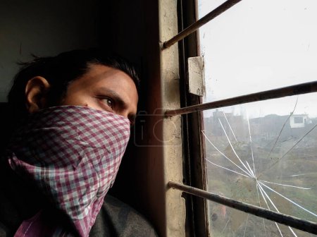Téléchargez les photos : 14 oct.2022 Uttarakhand, Inde. Un homme au visage à moitié couvert regardant par la fenêtre d'un train en Inde. Mystérieux voyage - en image libre de droit