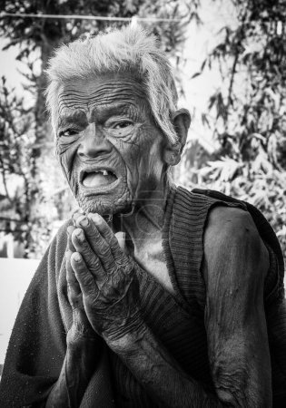 Photo for Oct.14th 2022 Uttarakhand, India. Artistic monochromatic shot of an Indian elderly lady, in Namaste pose, gazing at the camera with spiritual grace. Serene Indian monk. - Royalty Free Image