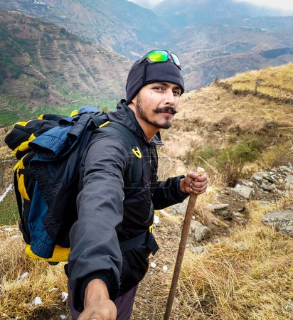 Photo for October 14th 2022 Uttarakhand, India. Hiker with selfie stick captures trekking expedition in Nag Tibba mountains, Uttarakhand, India. Exciting stock media for adventurers - Royalty Free Image