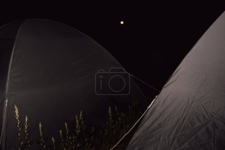 Photo for Night view: Campground in Uttarakhand, India, with foreground campsites, under the captivating sight of a full blood moon. - Royalty Free Image
