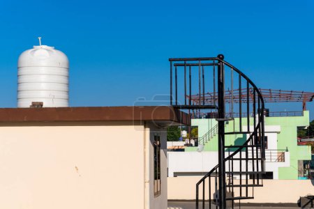 Urban Living: Rooftop View of Overhead Water Tank and Metal Staircase in Dehradun, India