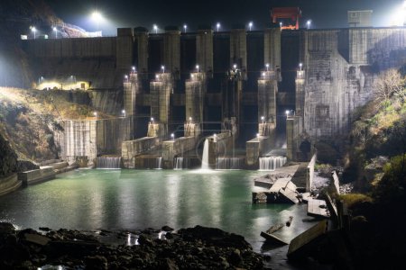 18 février 2024, Uttarakhand Inde. Tournage de nuit cinématographique du barrage de Lakhwar-Vyasi sur Yamuna Riveer avec de l'eau qui coule d'une sortie avec des murs de barrage éclaircis. Village de Juddo
