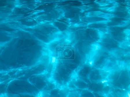 Téléchargez les photos : Belle image de fond de surface de piscine bleue. Eau propre couleur de rêve tranquille avec des ondulations lumineuses. - en image libre de droit