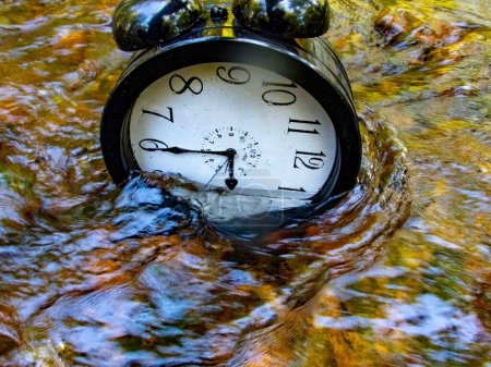 Photo for Concept image losing track of time, relativity science image, climate change, flowing time, large clock in a flowing stream with half of the clock face submerged with ripples and colors distorting the - Royalty Free Image