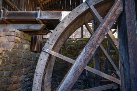 Side view of section of a giant historic water wheel for hydropower with sleuce spillway. Woodgrain detail and rustic weathered texture. No people
