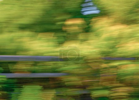 Abstract blurred intentional camera movement image, ICM, with yellow flowers and split rail wooden fence in a soft nature background meadow image with no people and copy space.