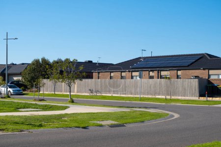 Photo for Background texture of a suburban street in an Australian neighbourhood with single storey residential house, family car parked on side of the asphalt road, grass nature stripe. Copy space - Royalty Free Image