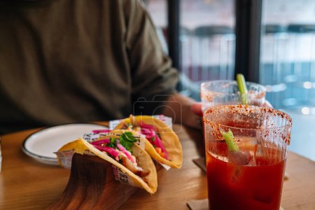 Foto de Tacos and a michelada at a restaurant table. High quality photo - Imagen libre de derechos