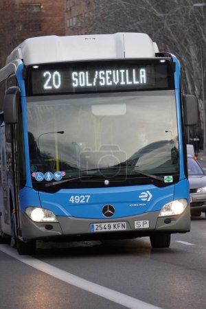 Foto de Madrid, Spain. 30 December 2022. Vertical shot of a gas-powered intercity bus, line 20 of Madrid's Sol-Sevilla line circulating along a street in the Moratalaz neighborhood. - Imagen libre de derechos
