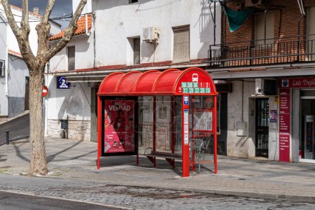 Photo for Bus stop with covered red bus shelter and a bench to sit on in Calle Real in Arganda del Rey. - Royalty Free Image