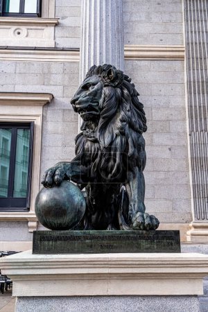 Foto de Madrid, España. 15 de abril de 2023. Imagen vertical de uno de los leones de bronce que protegen la entrada del congreso de España, en madrid, fundido con cañones de la guerra de África. - Imagen libre de derechos