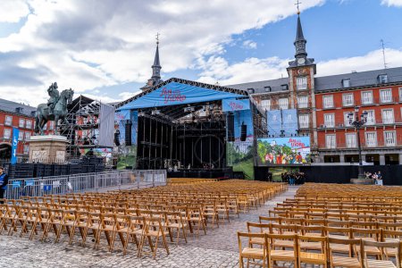 Foto de Madrid, España. 15 de mayo de 2023. Escenario musical San Isidro 2023 ubicado en la plaza principal con muchas sillas plegables de madera para el público. - Imagen libre de derechos