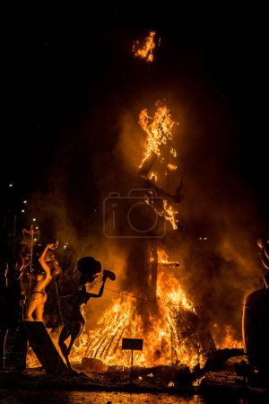 Foto de Imagen vertical de una estructura de madera en llamas durante la celebración de la víspera de San Juan, el 24 de junio, donde se queman las figuras de las hogueras. - Imagen libre de derechos