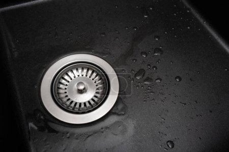 Foto de New granite kitchen sink black wash flat lay. After. Drops water. House cleaning service. Top view. - Imagen libre de derechos