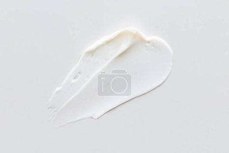 Foto de Muestra de textura crema blanca, cosméticos para la cara y el cuerpo sobre un fondo gris claro aislado. Mancha.. - Imagen libre de derechos