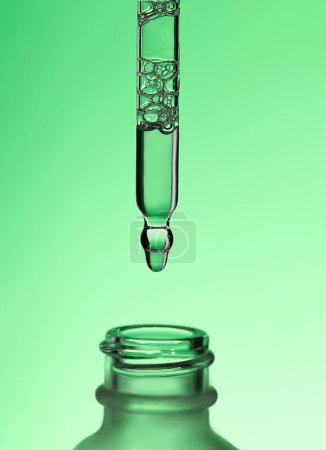 Pipette serum with clear liquid niacinamide, hyaluronic or Aha Bha acids on a green isolated background. Textured swatch skincare. Laboratory cosmetic