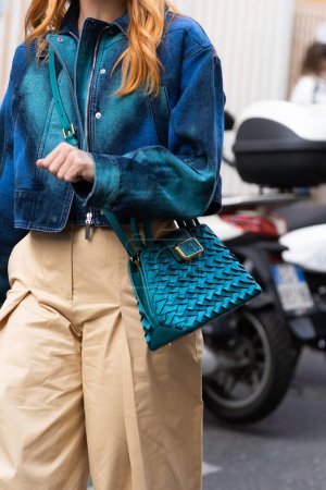 Téléchargez les photos : Milan, Italie - septembre, 21, 2022 : Femme portant une veste en denim imprimé cravate et colorant bleu et vert, un pantalon large beige, un sac à main tressé en cuir bleu-vert brillant de l'Alberta Ferretti - en image libre de droit