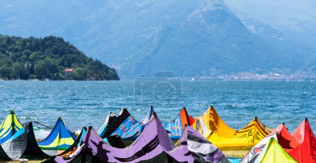 Foto de Kite surf tabla y cometas contra el lago y las montañas, kitesurf en el lago Como, Alpes, Italia. Concepto de deporte de viaje activo - Imagen libre de derechos