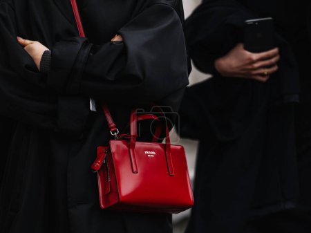 Foto de Milán, Italia - 23 de febrero de 2023: mujer vestida de rojo Prada Re-Edition 1995 mini bolso de hombro. Detalles del atuendo de blogger de moda, estilo callejero - Imagen libre de derechos