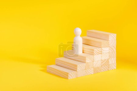 Businessman climbing stairs. Business growth success process, career ladder. Ambitions concept. Wooden figurine on yellow background