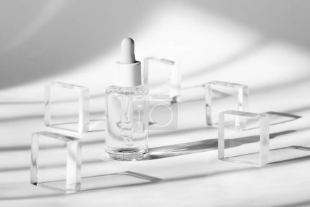 Serum-Kosmetikflaschen-Attrappe auf transparentem Acrylblock-Sockel auf weißem Hintergrund, Schatten von der Sonne, natürliches Licht aus Fenstern. Geometrischer Stand, Podium für Kosmetik, Produktpräsentation