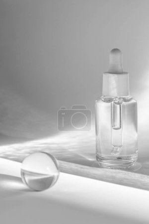 bouteille de sérum clair et cristal boule de coulée réflexions de lumière sur un fond blanc, paquet de produits cosmétiques