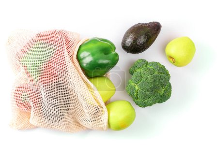 Assorted fresh produce including green apples, bell peppers, avocado, and broccoli in an eco-friendly mesh bag on a white background, emphasizing healthy eating and sustainability