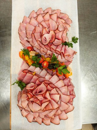 Photo for Slices of ham arranged on a wooden platter with vegitables for buffet - Royalty Free Image