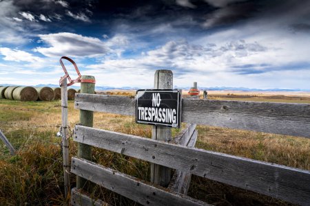 Foto de Longview Alberta Canada, 16 de octubre de 2022: Una señal de no invasión en una puerta con vistas a las balas de heno redondas y las montañas rocosas canadienses en las praderas canadienses. - Imagen libre de derechos