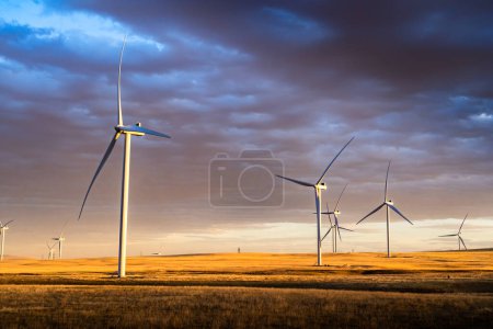 Foto de Parque eólico al atardecer bajo un cielo colorido produciendo energía sostenible en las praderas canadienses cerca de Pincher Creek Alberta Canadá. - Imagen libre de derechos
