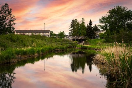 Foto de Pequeño arroyo en un área de recreación comunitaria con una puesta de sol que refleja el agua en Nose Creek Park Airdrie Alberta Canadá. - Imagen libre de derechos