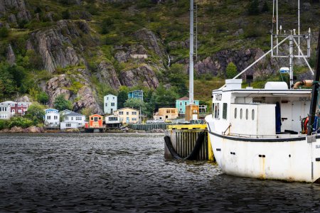Photo for St John's Newfoundland Canada, September 22 2022: Fishing boat moored at harbour with the Battery Road jelly bean homes at background. - Royalty Free Image