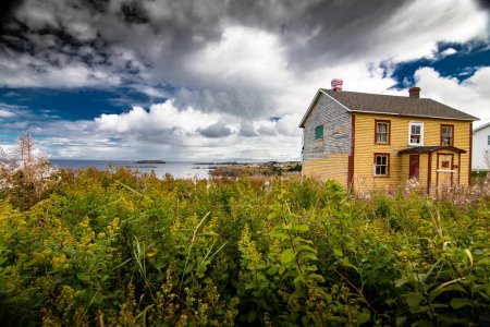 Téléchargez les photos : Maison abandonnée surplombant l'océan Atlantique aux couleurs automnales près d'Elliston Terre-Neuve Canada sous un ciel dramatique bleu profond. - en image libre de droit